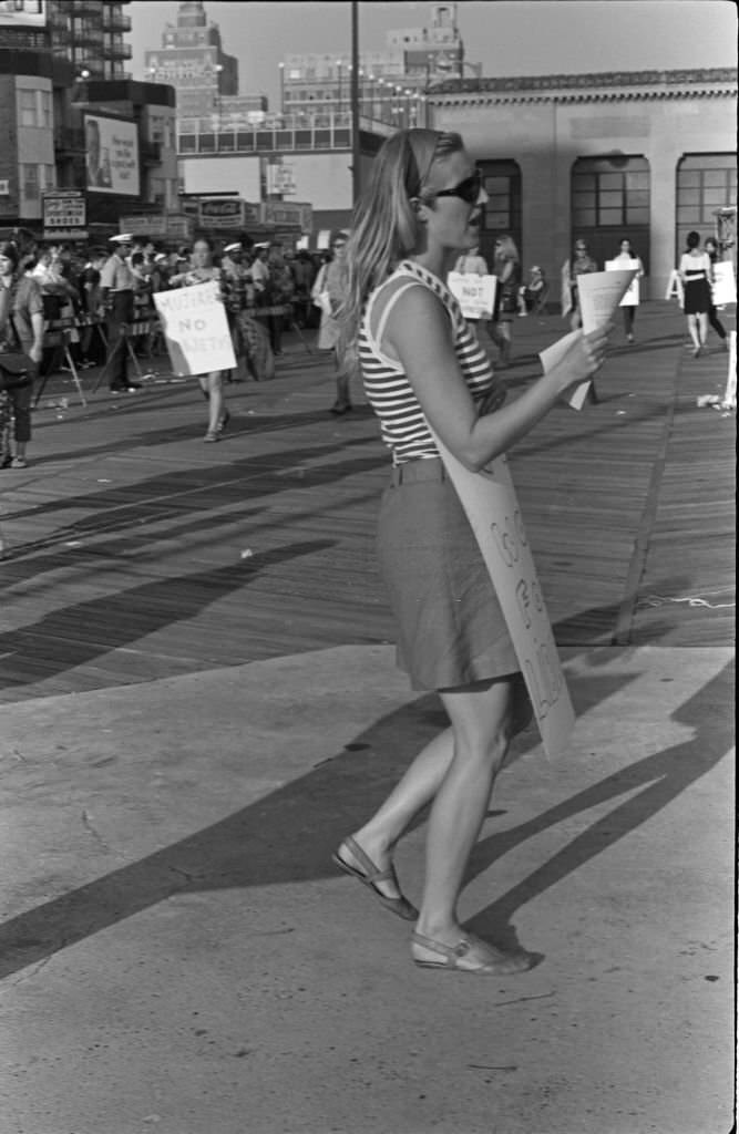 #24 Demonstrator Peggy Dobbins, among others (many with posters) protest the Miss America beauty pageant, Atlantic City, New Jersey, September 7, 1968.