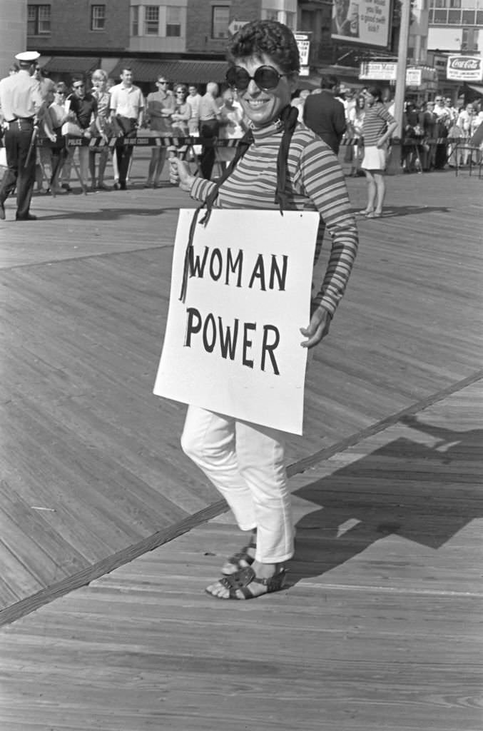 #28 A demonstrator carries a poster that reads ‘Woman Power’ as she protests the Miss America beauty pageant, Atlantic City, 1968.