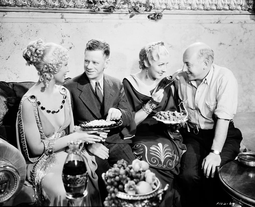 Cecil B DeMille eating food with a group of people during the making of the film ‘Samson and Delilah’, 1949