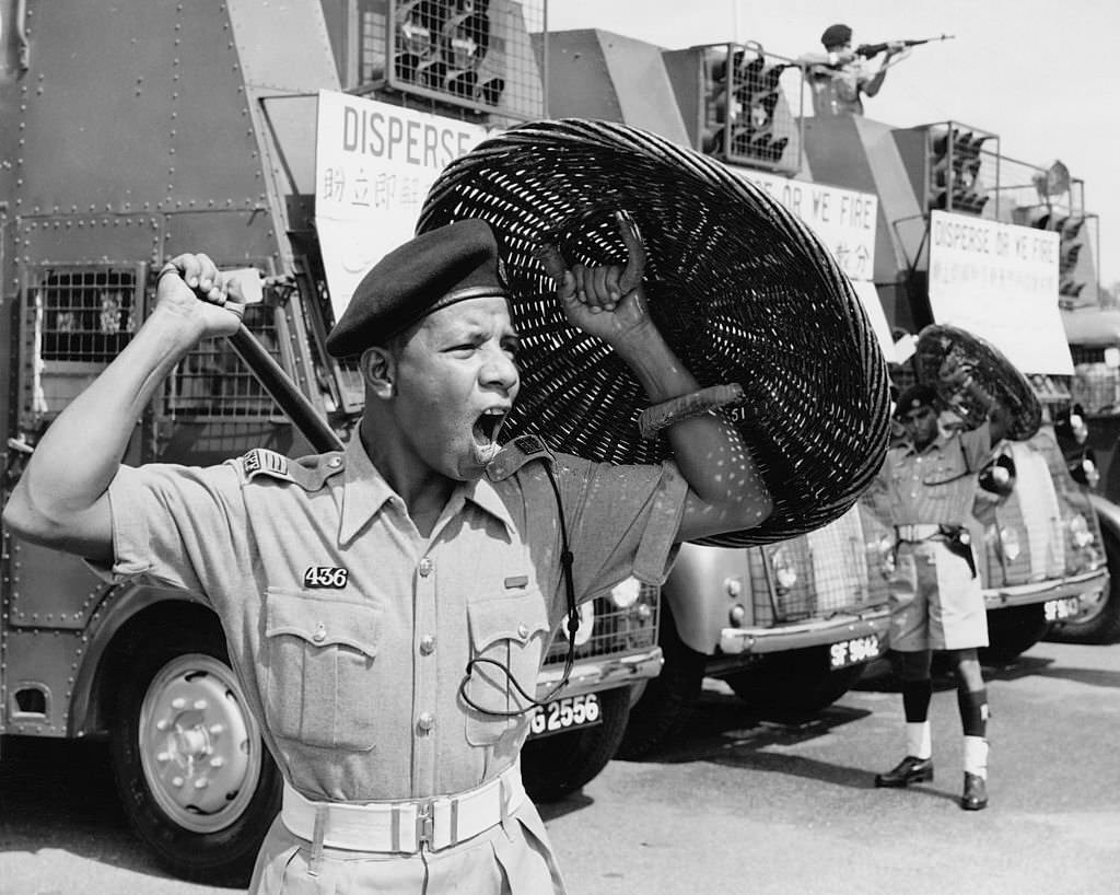 #23 Members of the Singapore Police Riot Squad armed with truncheons and wicker riot shields during race riots between Chinese and Malay groups in Singapore, 1964.