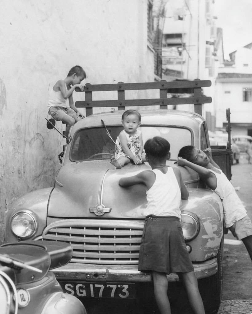 #48 Children in Singapore clamber over a parked van, 1962