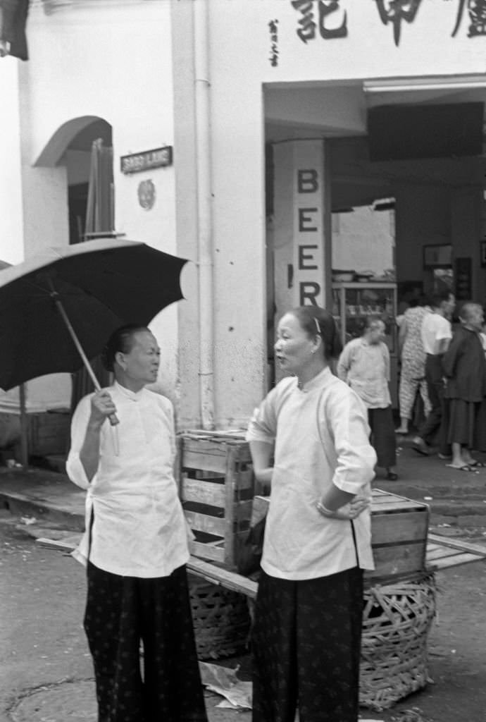 #79 Two Asian women chatting outside a shop in Singapore, 1962