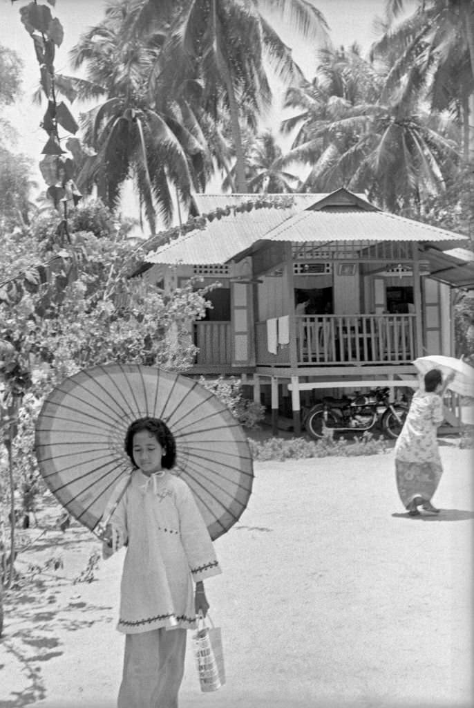 #86 Asian little girl walking protecting herself from the sun under a parasol, Singapore, 1962