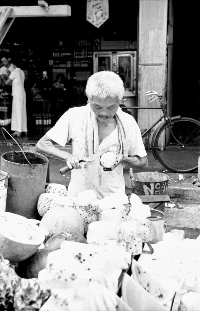 #89 Street vendor peeling fruits in an outdoor food market, Singapore, 1962