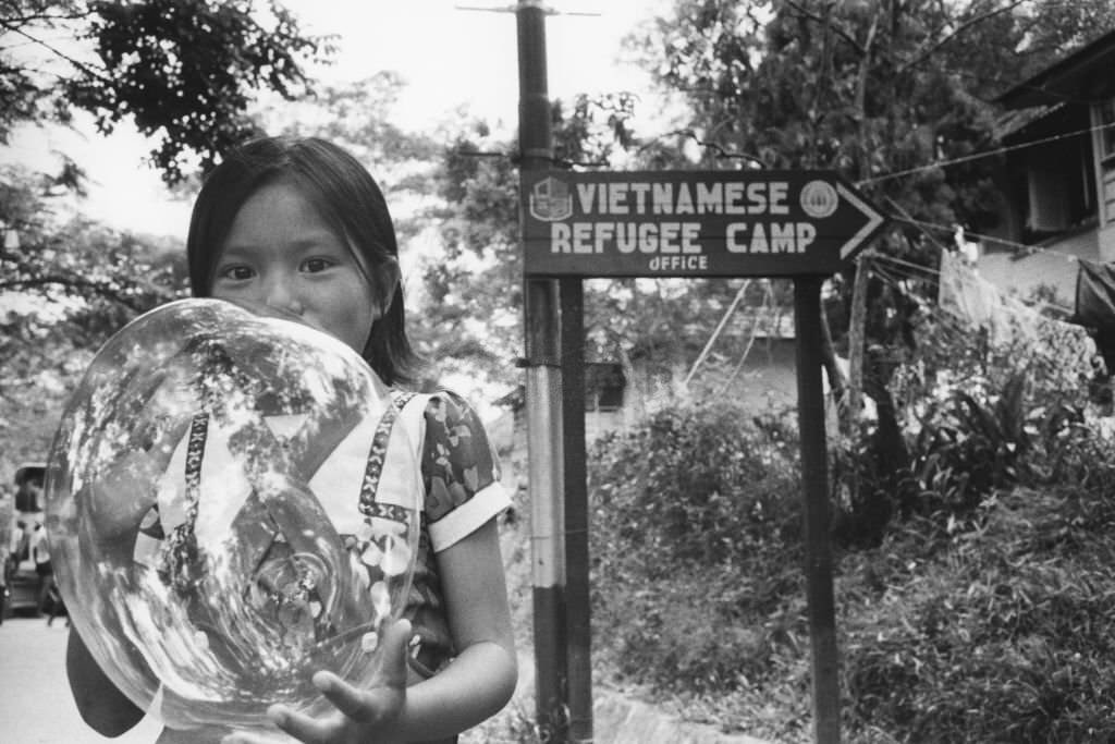 #70 A little girl blowing bubbles at Hawkins Roadd Vietnamese refugee camp in Singapore, July 28, 1979.