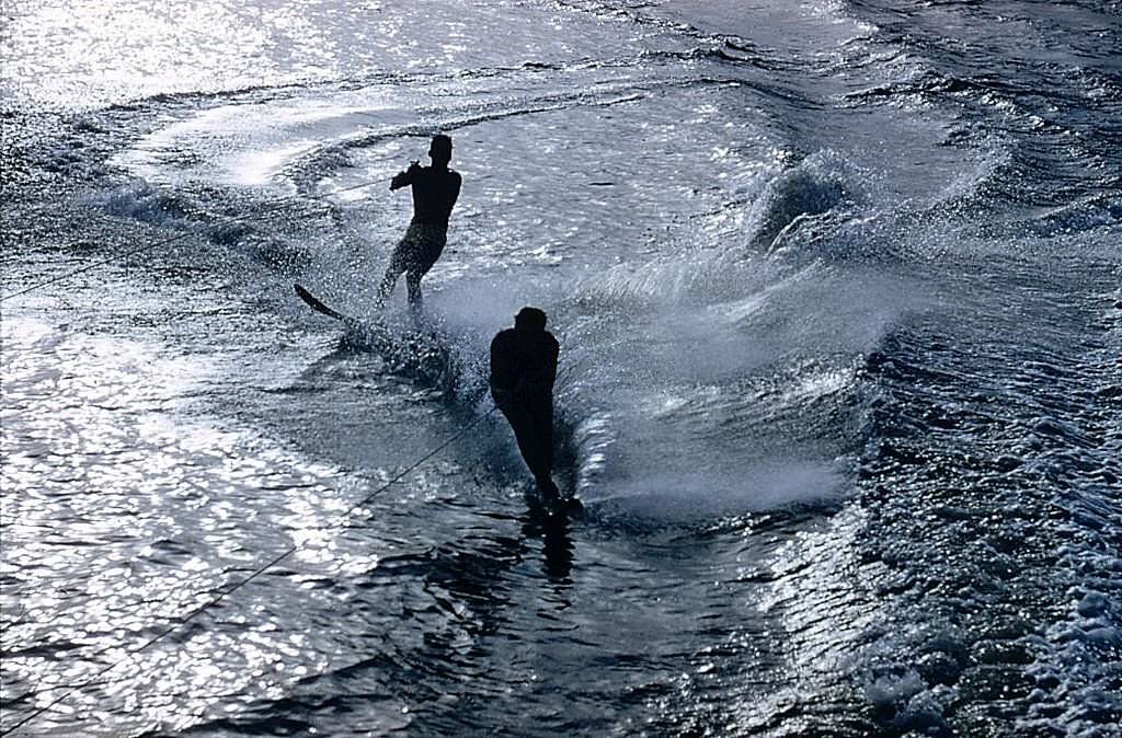 #125 Water-skiers at Cypress Gardens, Florida are silhouetted against silver water, 1970