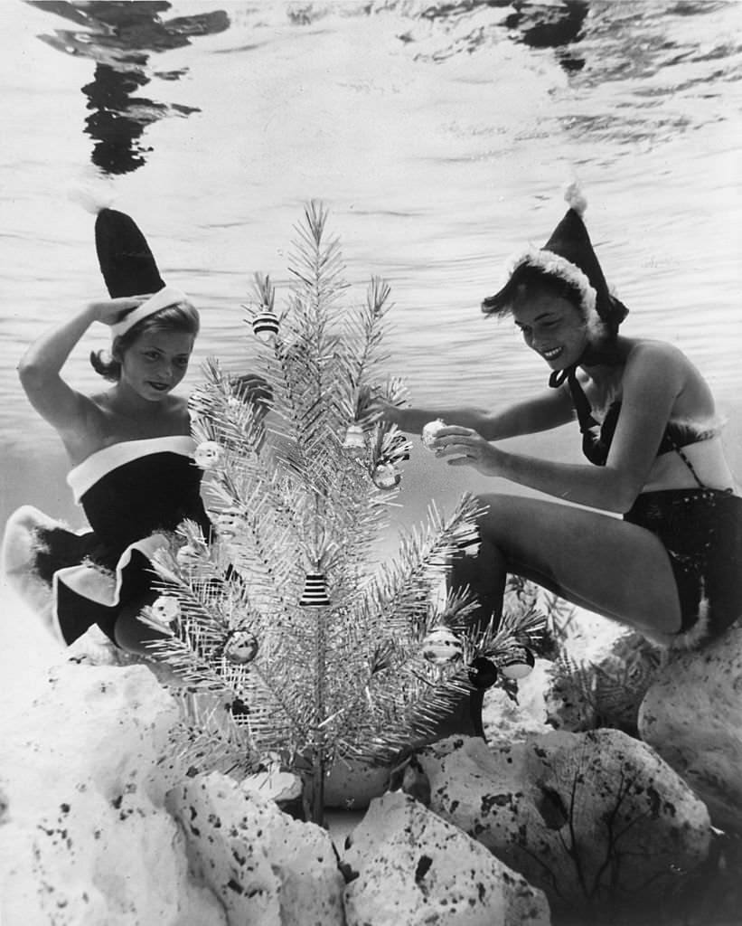 #128 Two of Santa’s more alluring helpers decorate an underwater Christmas tree in a pool at Cypress Gardens, Florida, 1968