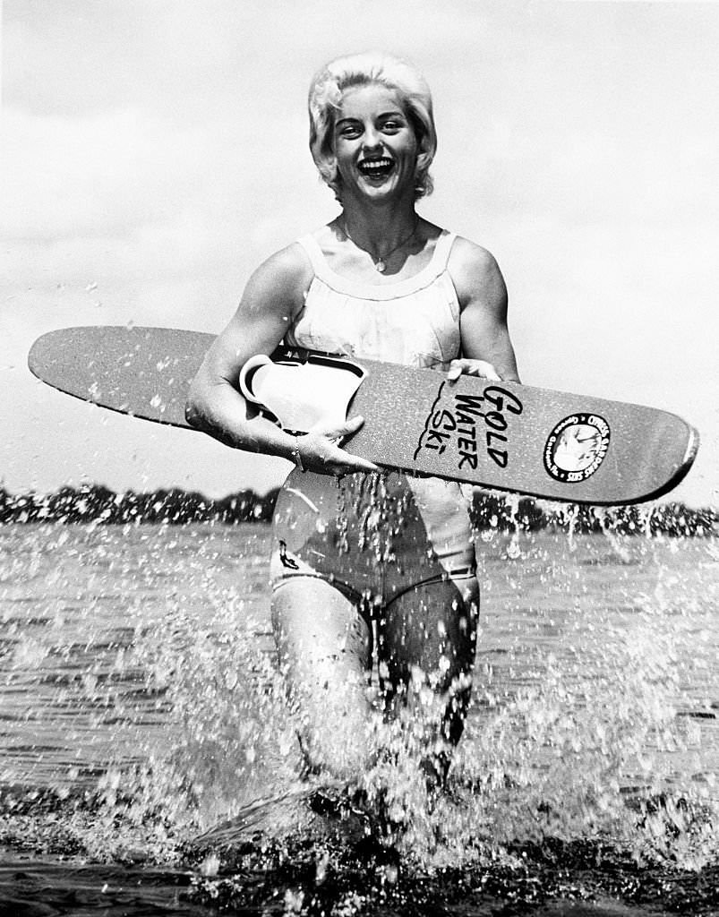 #146 Splashing out of the water, Barbara Cooper Clack, who just set a world’s record of 102 feet to win the Women’s Ski Jumping Championship, shows her support with her ski.