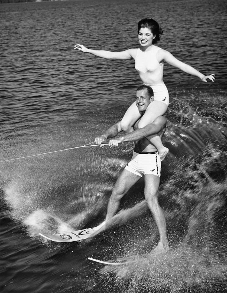 #148 Donna Axum, Miss America of 1964, rides on the shoulders of water skiing champion Don Seyez as they perform the “doubles act” at Cypress Gardens, Florida. June 23, 1964.