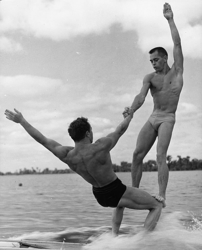 #155 Two athletes practising a gymnastic ‘aqua acrobatic’ exercise on a water toboggan at Cypress Gardens, Florida, 1963