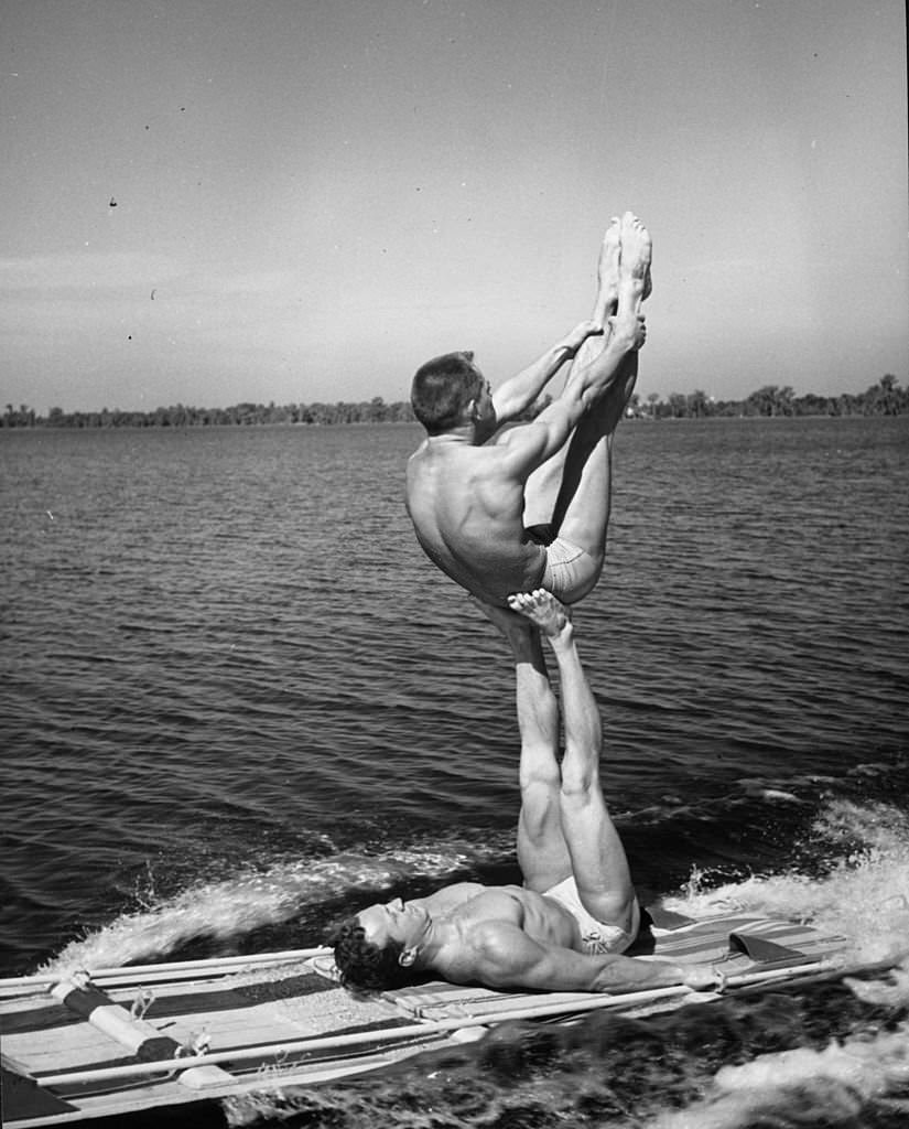 #156 Two athletes practising a gymnastic ‘aqua acrobatic’ exercise on a water toboggan at Cypress Gardens, 1963