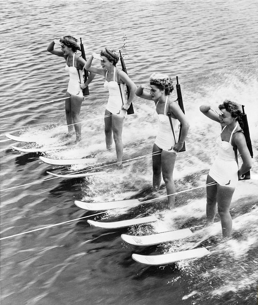 #33 four women on water skis: they wear bearskin hats and rifles at Cypress Gardens, 1955