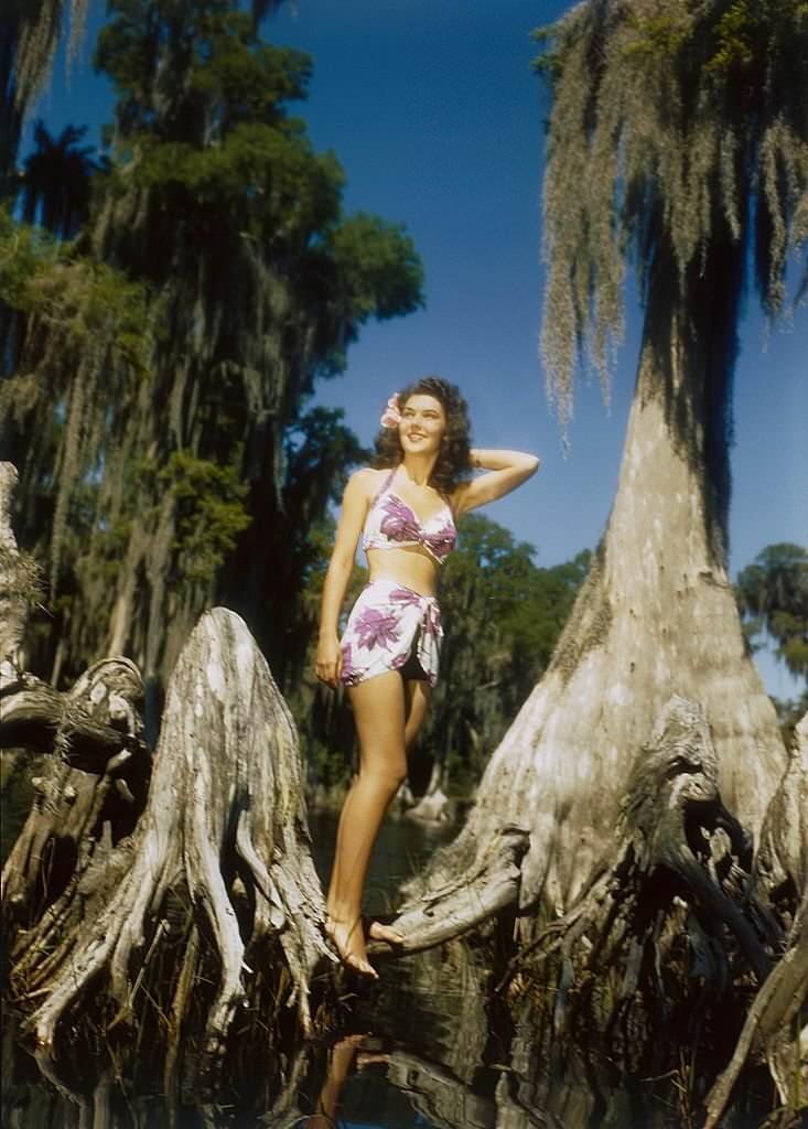 #63 A southern belle model poses by a Cypress tree at Cypress Gardens theme park in 1953 near Winterhaven, Florida.