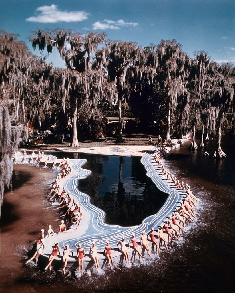 #76 A group of southern belle models pose for a portrait by a pool shaped like the state of Florida at Cypress Gardens theme park in 1953 near Winterhaven, Florida.