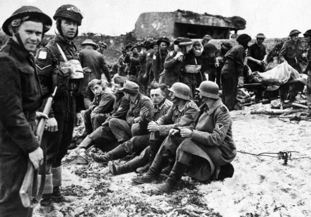#10 Canadian invasion troops stand guard over the first German prisoners captured during the assault on France by Allied forces on June 6, 1944 along a 100 mile front on the Normandy coast between LeHavre and Cherbourg.