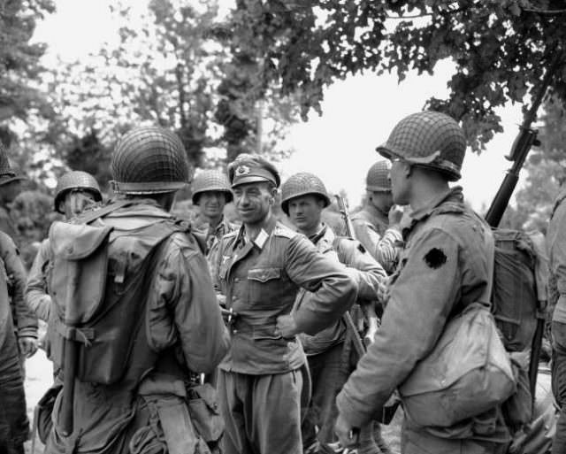 #18 A German officer smiles as he is interrogated by American soldiers who landed on the beaches of Normandy, France on June 12, 1944.