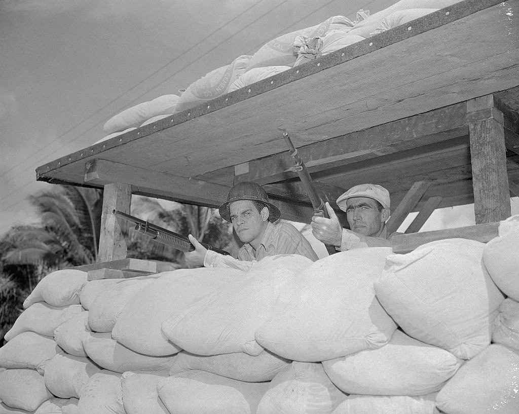 #110 These two men, behind makeshift sand barricades, are two company employees, who take time out from their regular work, to stand guard with rifles cocked, against any possible Japanese move.