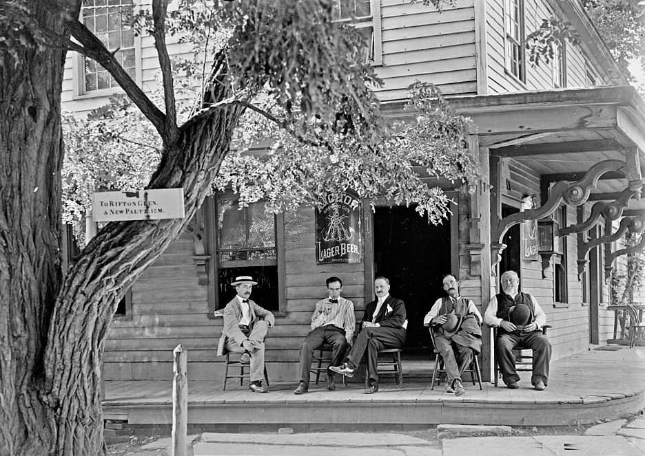 #129 Five men sitting on the porch of a building that has Anchor Lager Beer signs next to its entrances, 1904.
