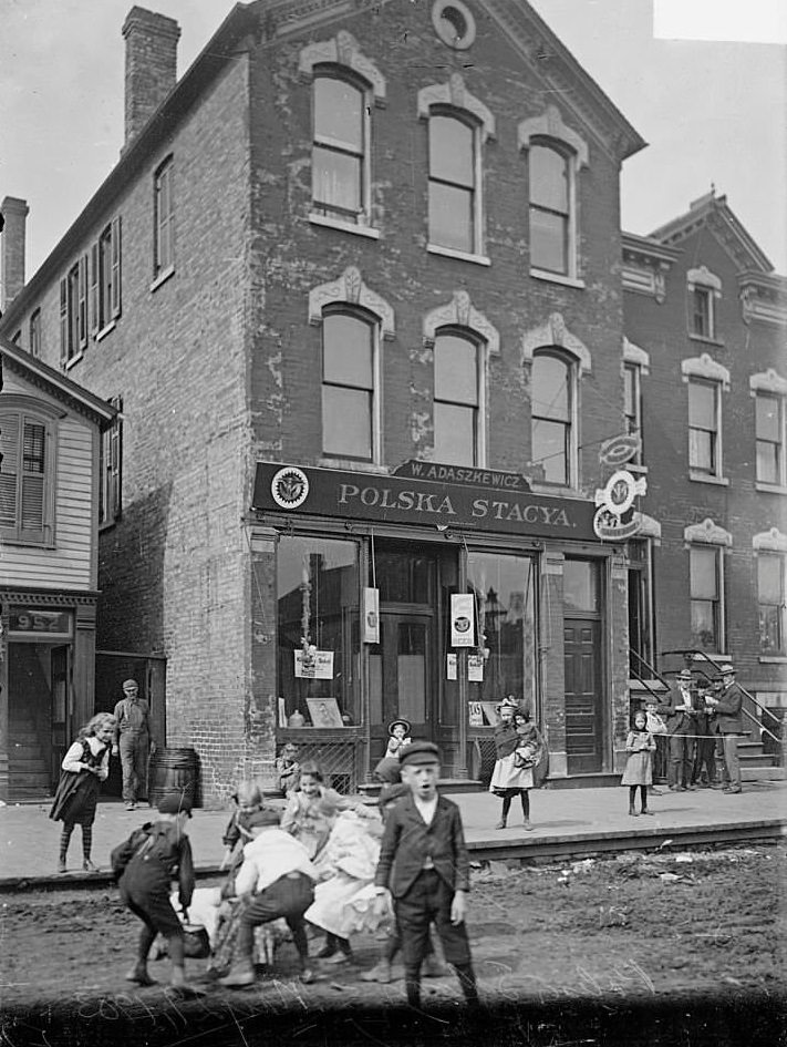 #136 Polska Stacya, a Polish saloon, with children playing and men standing nearby, Chicago, Illinois, May 29, 1903.