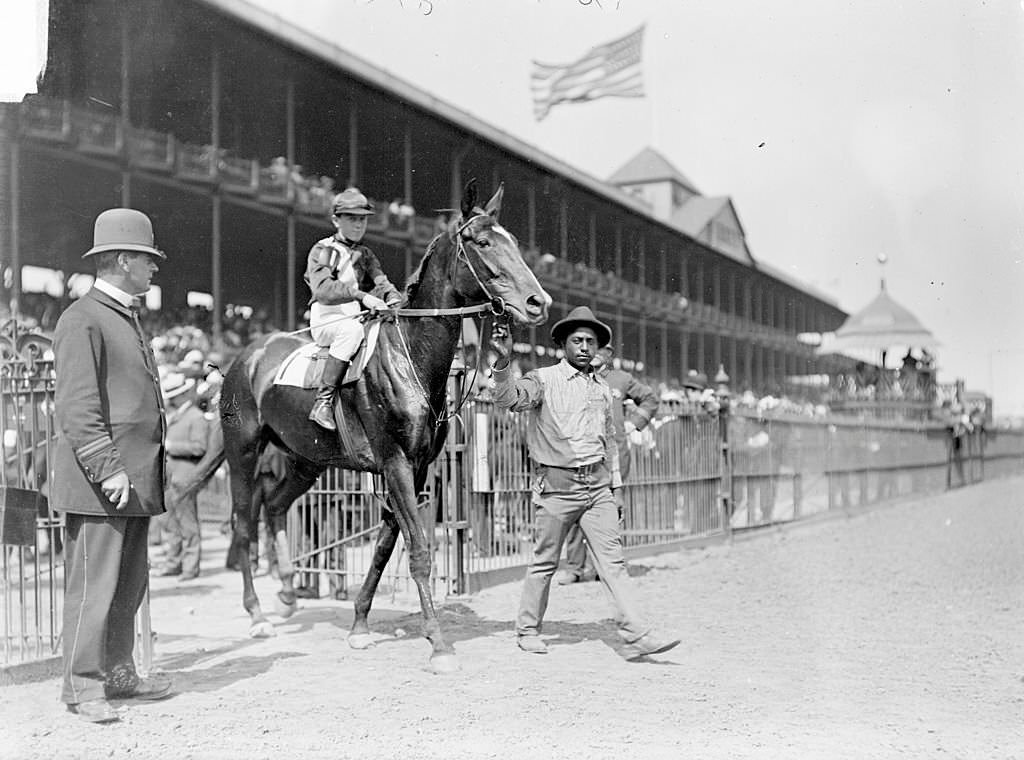 #156 Racehorse, Lute, with jockey mounted, being led on track by African American handler, Washington Park Race Track, Chicago, 1903.
