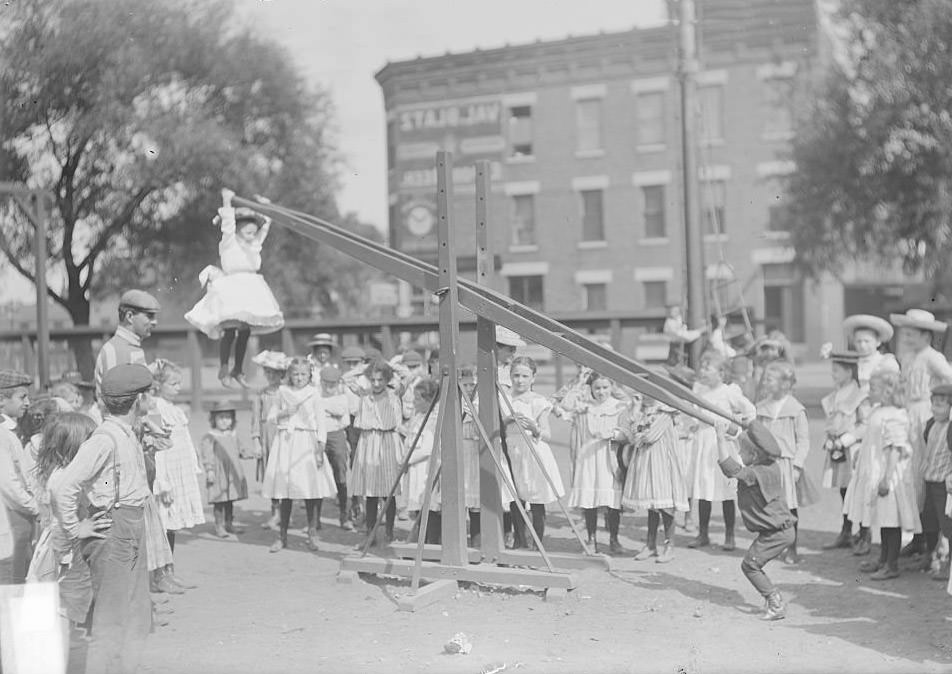#161 Children playing on a seesaw at the Webster School playground, located at Wentworth Avenue and 33rd Street in the Douglas neighborhood, Chicago, Illinois, August 19, 1902.