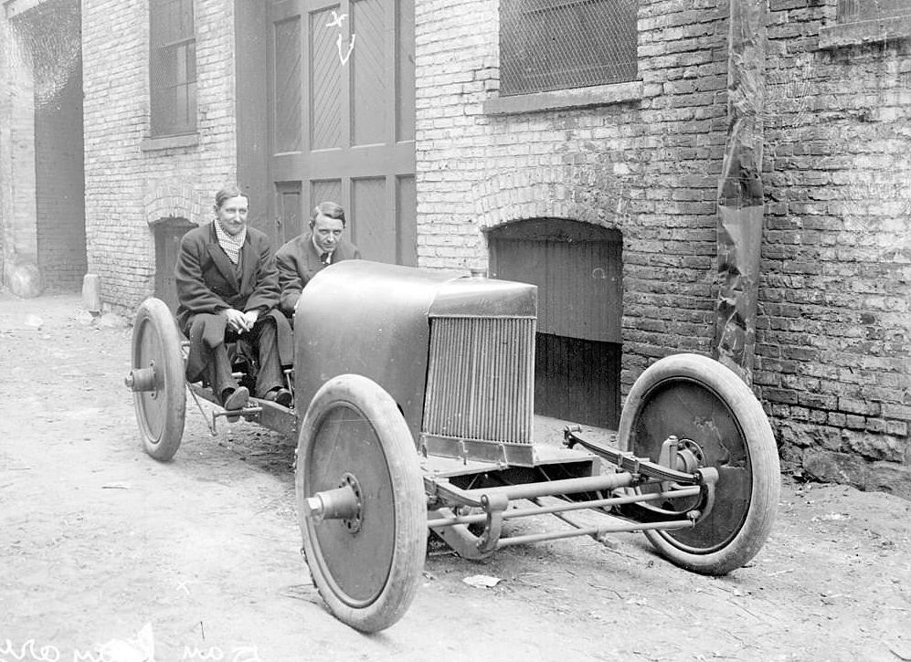 #48 Group portrait of Barney Oldfield and Dan Canary, motorists, sitting in a car parked next to a garage in Chicago, Illinois, 1905.