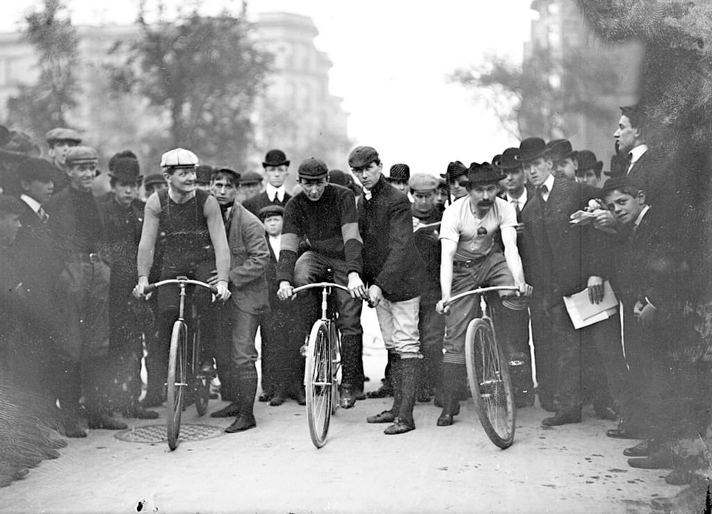 #70 Cyclists, J. E. Gill, C. A. Linde, Ed Bukowski , positioning on their bicycles in front of a crowd on North Michigan Avenue in the Near North Side community area of Chicago, Illinois, 1901.