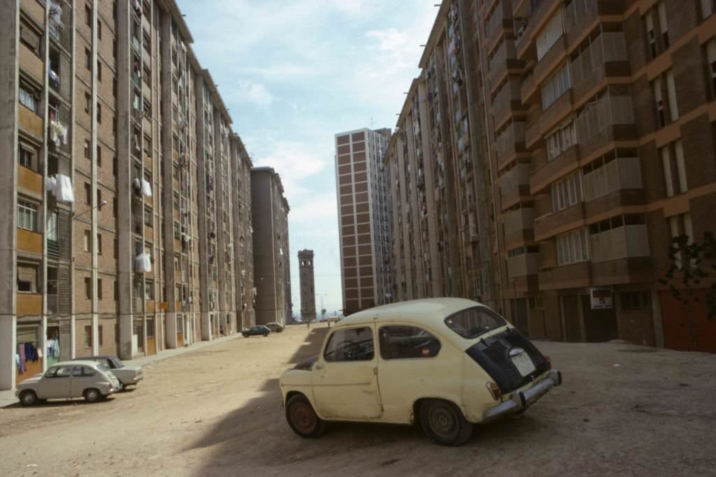 #113 Fiat 500 car dented and parked between buildings in the Cornella district, May 1977, Barcelona, Spain.