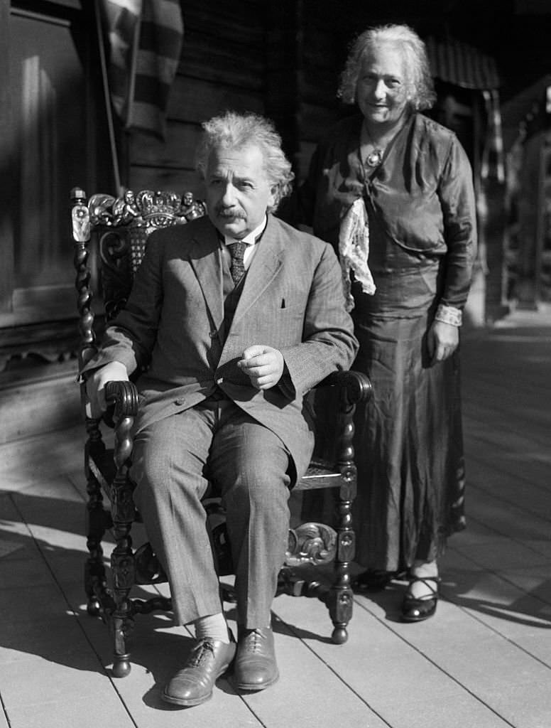 #64 Albert and Elsa Einsteinn California. He is seated while she stands behind him.