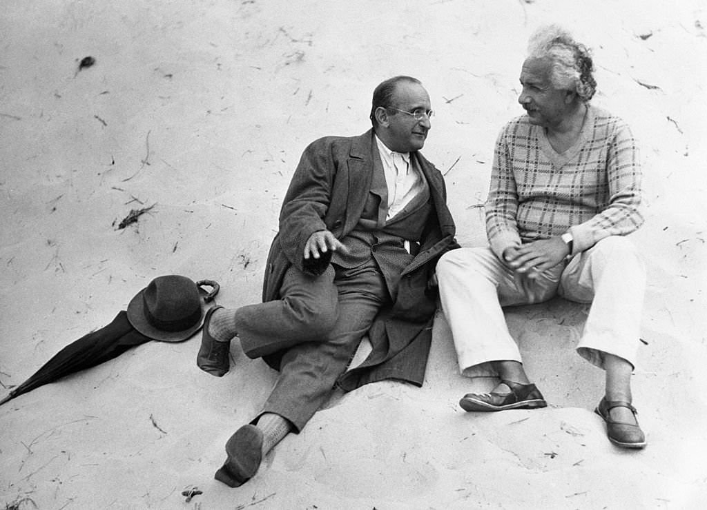 #42 Albert Einstein and his colleague, Professor Walther Mayer of Vienna, go into a little relaxing dialogue on the beach at Coq-sur-Mer, Belgium,.