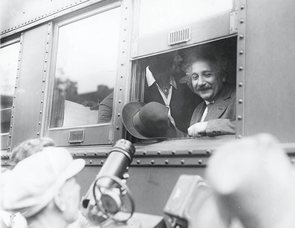 #100 Albert Einstein smiles at supportors and newsmen out of the window of a train, Chicago, Illinois, early 1930s.