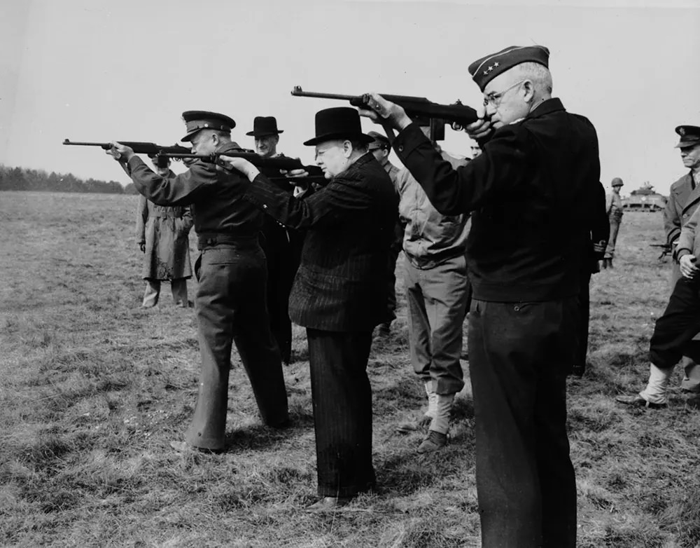 #9 Dwight D. Eisenhower, Winston Churchill and Gen. Omar Bradley fire carbines during a tour of an army camp in England, 1944.
