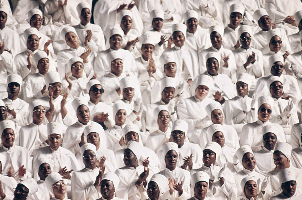 #32 Muslim women dressed in white applaud Elijah Muhammad during the delivery of his Savior’s Day Message in Chicago, March 1974.