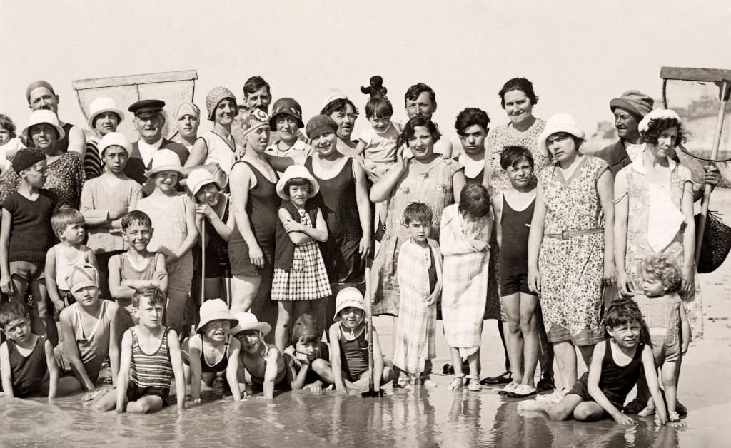 #18 A group of holidaymakers, several with nets, posing on the beach at Deauville, 1920