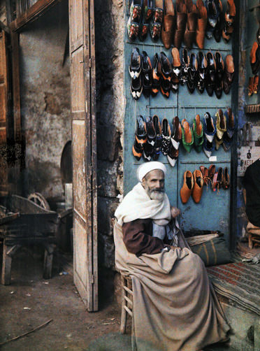 #12 Shoe vendor sits next to his store.