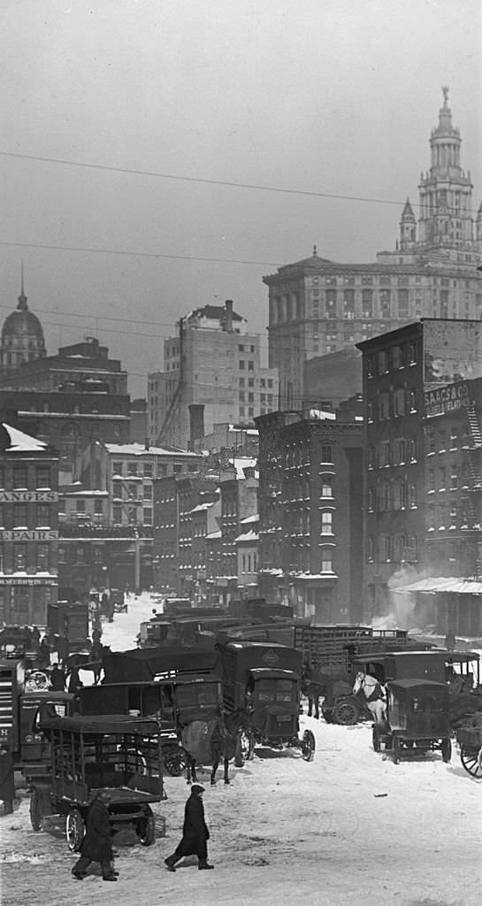 #118 A view of a group of automobiles and wagons parked in the snow at the Fulton Street Fish Market, in downtown Manhattan, New York City. 1920s