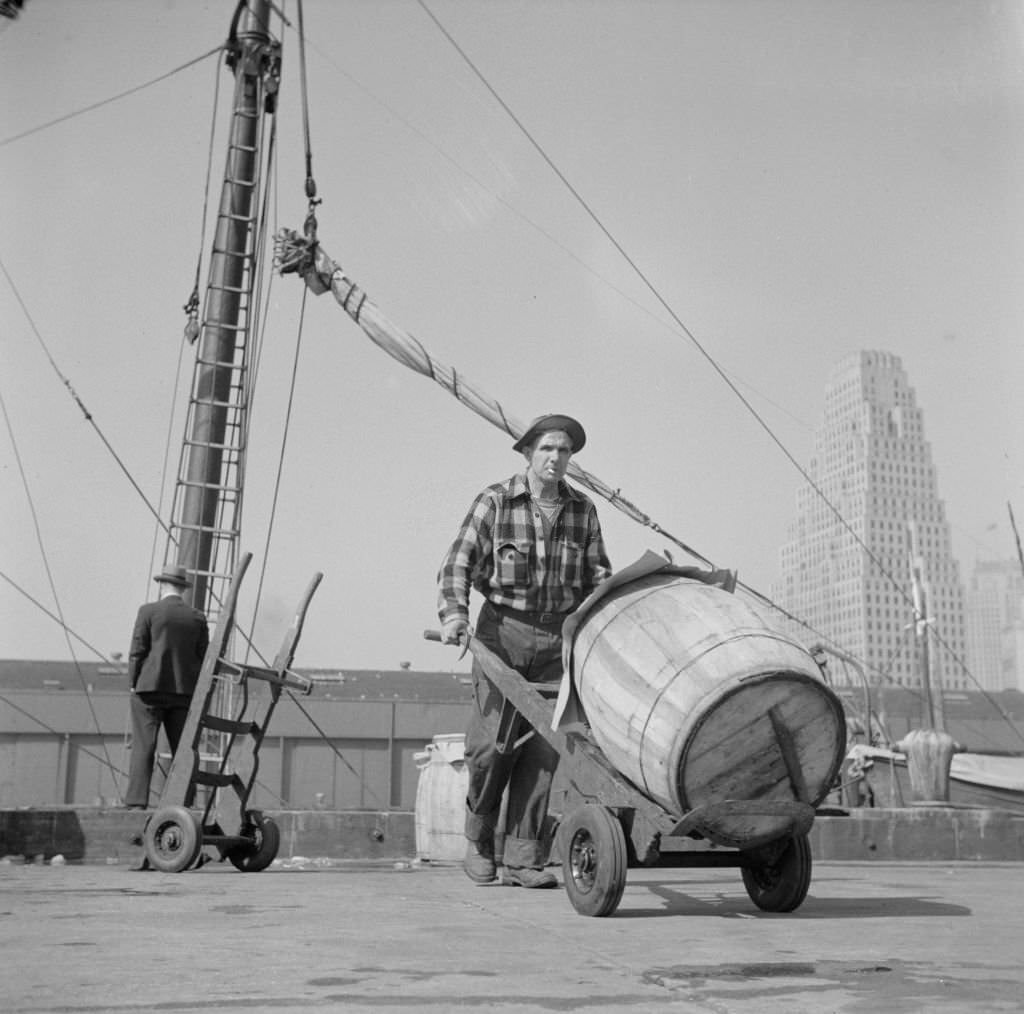 #136 Dock stevedore at the Fulton fish market moving a barrel of codfish. A