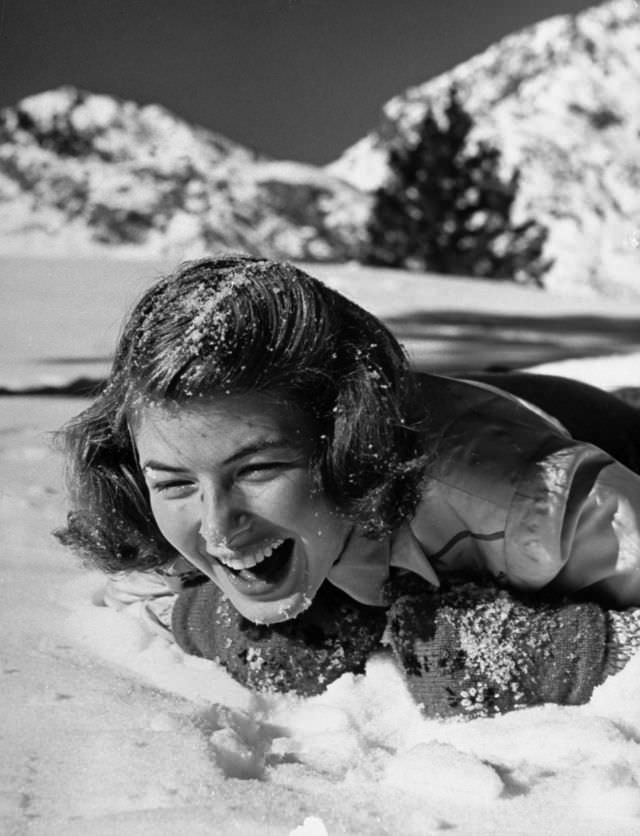 #5 Ingrid Bergman screaming with laughter as she lies splashed with snow by a playmate during her ski vacation at June Lake resort, 1941.