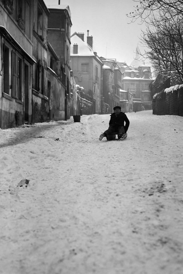#7 A boy sleds in the snow-covered rue de l’Abreuvoir in Montmartre, Paris, France, January 1945.