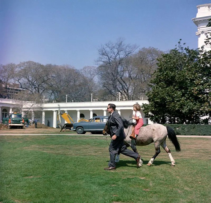 #3 Secret Service agent Bob Foster leads Caroline Kennedy on a ride with Macaroni.