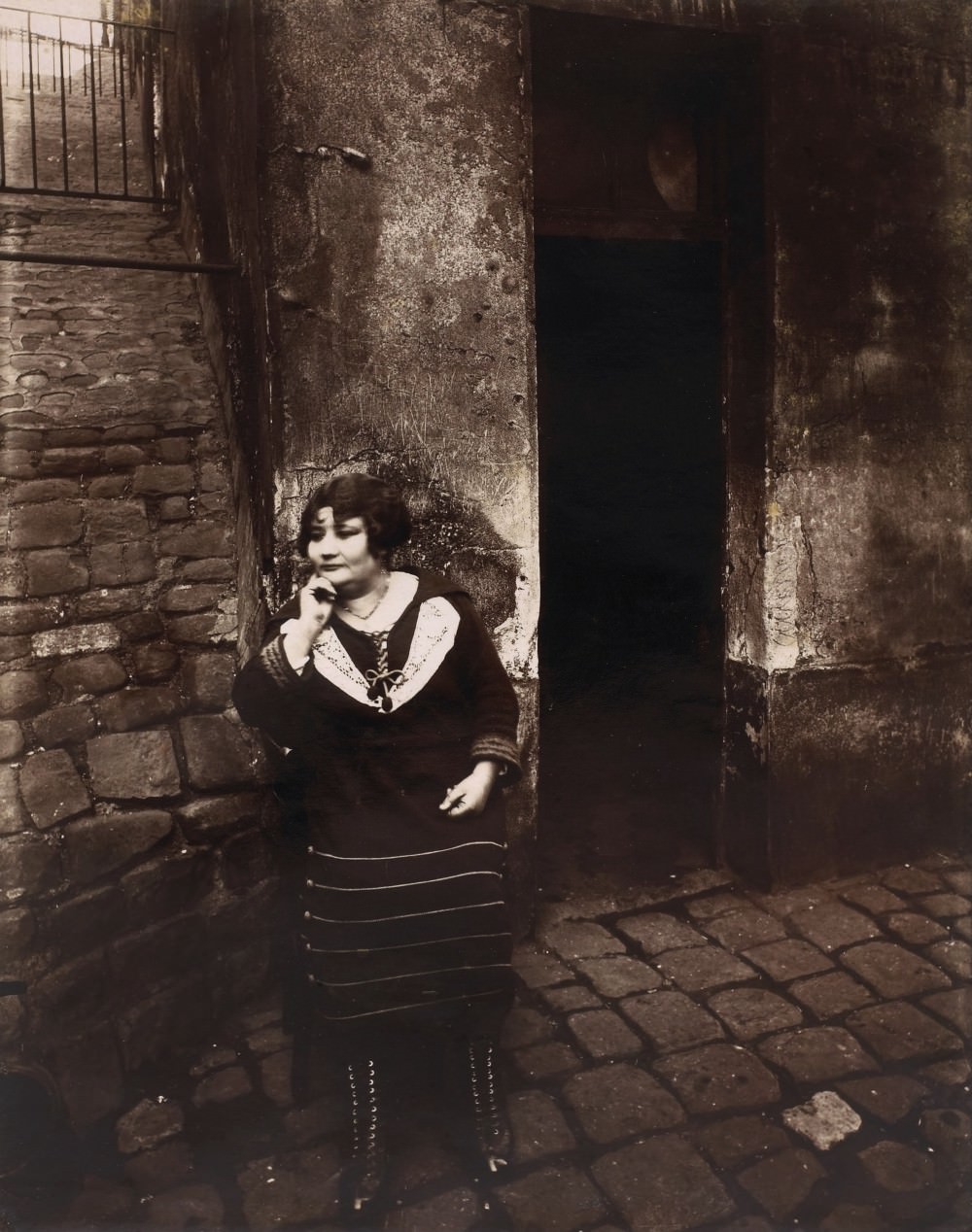 #7 La Villette, rue Asselin, a sex worker on her shift in front of her door, 1921.