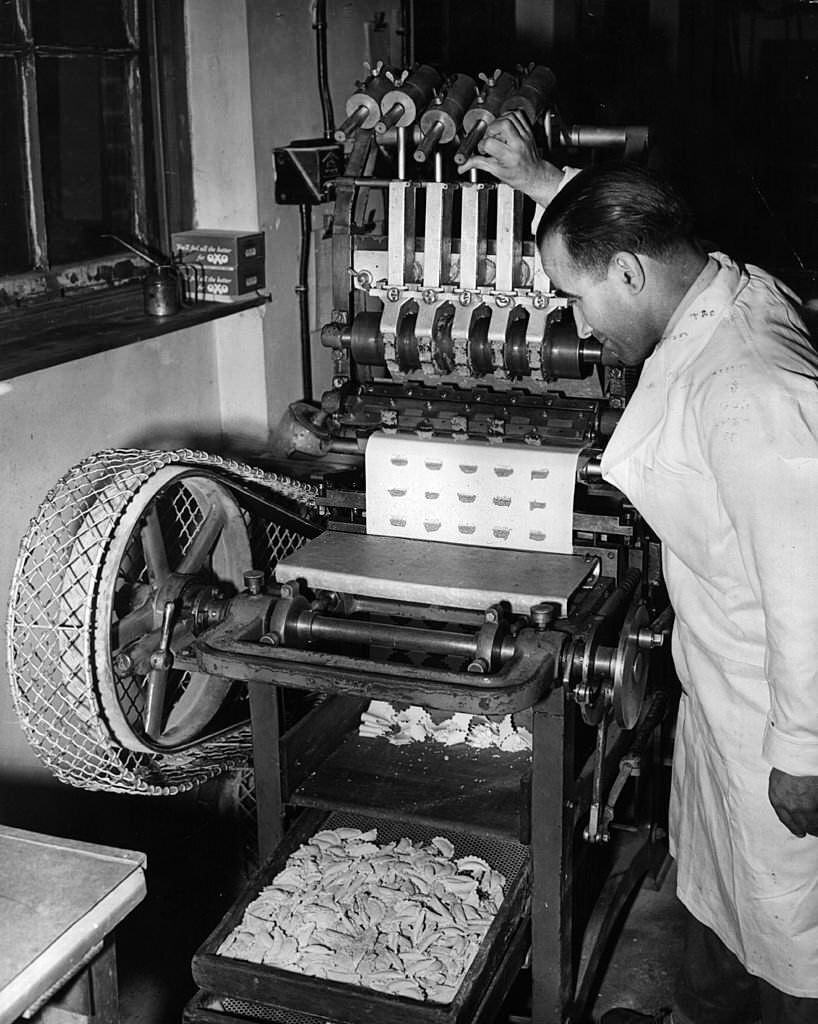 #35 Mr Michael Pino operates a ravioli-making machine at Messrs L Ugo Ltd, London, 1955. The factory specialises in all types of pasta and rivals the imported pastas from Italy.