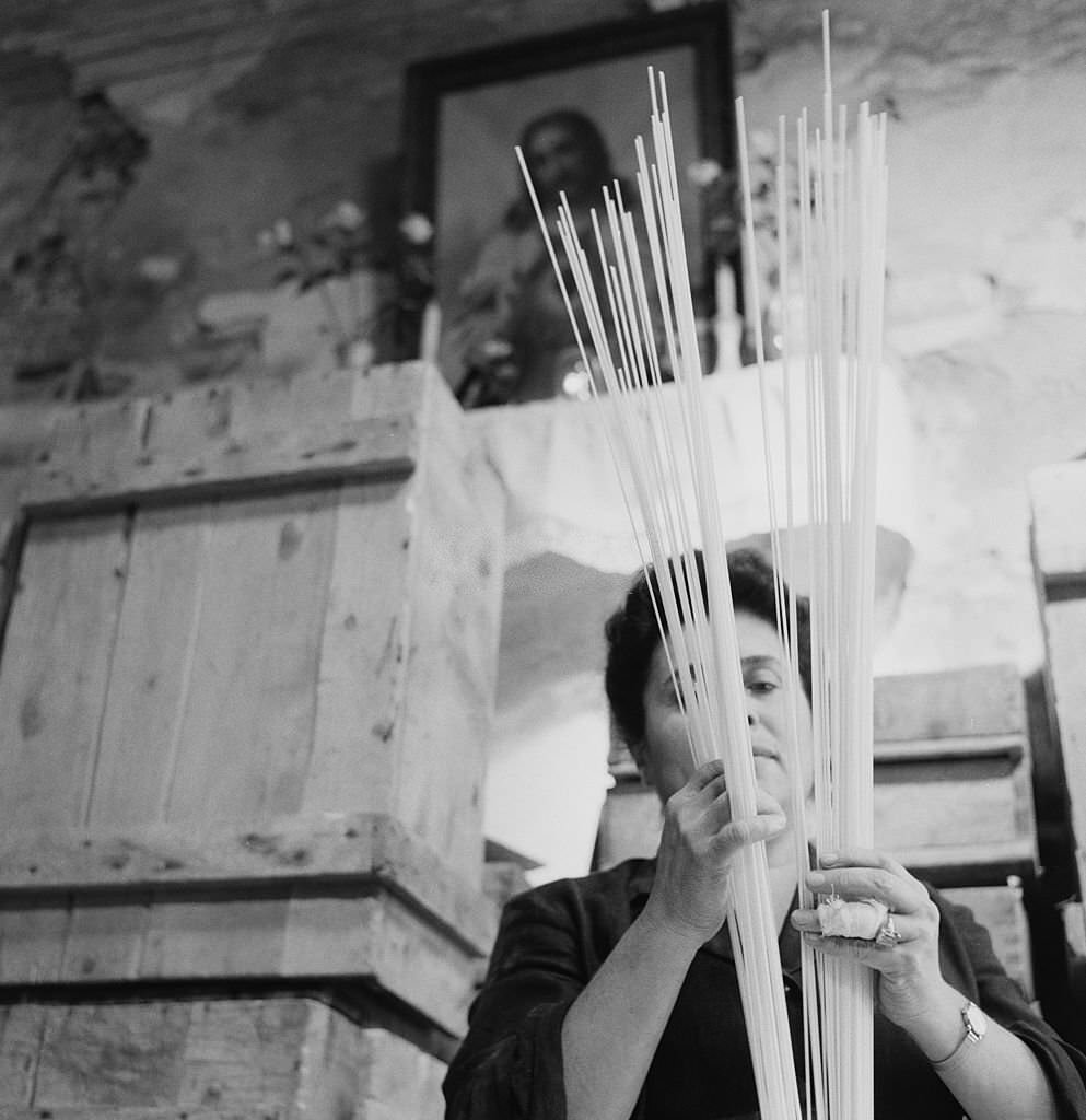#36 A woman holding strands of pasta, Italy, 1955.