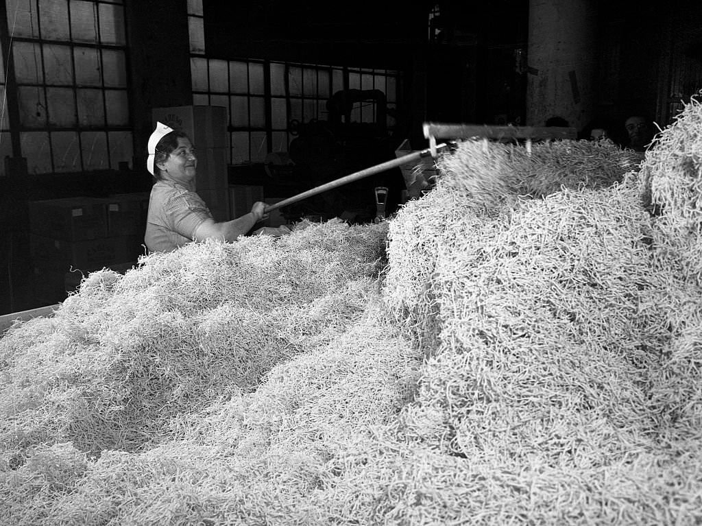 #43 A worker at the Atlantic Macaroni Company, makers of Caruso brand products, keeping the chute clear of finished macaroni in Long Island City, New York, 1943