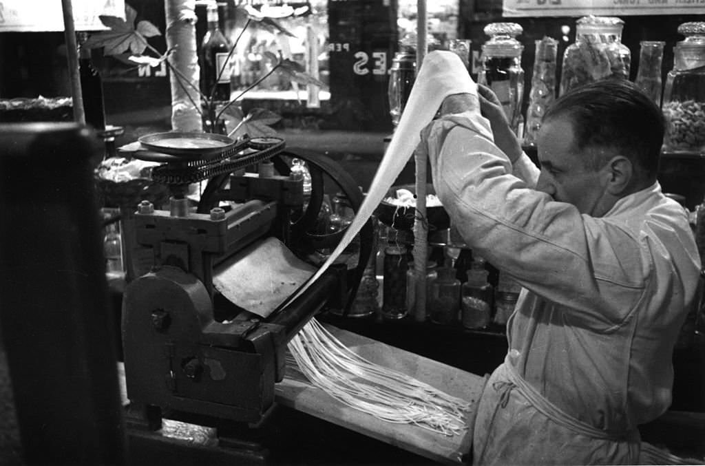 #49 Lengths of pasta are cut into strips by machine in Recchioni’s restaurant ‘King Bomba’ in London’s Soho, 1939