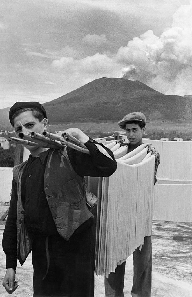 #55 Spaghetti production Two men carrying spaghetti on a bamboo stick to dry them, 1932