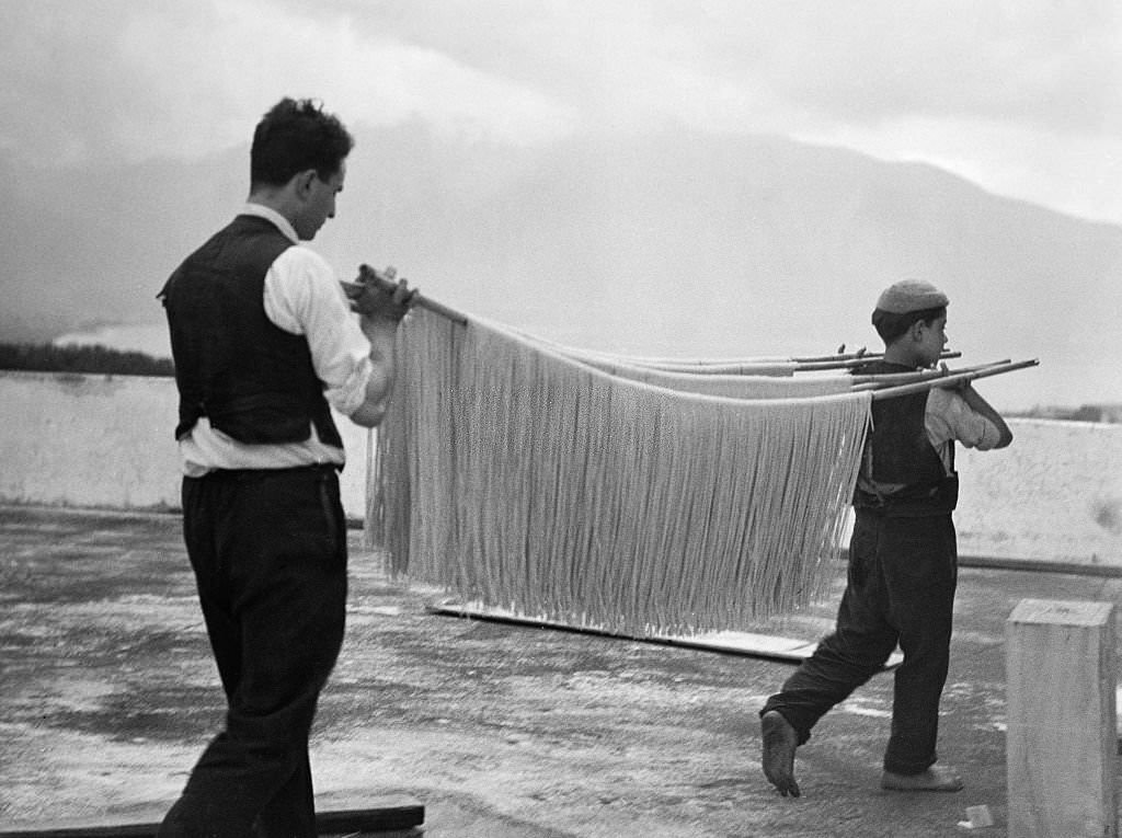 #62 Spaghetti production Carrying spaghetti on a bamboo stick to dry them, 1932