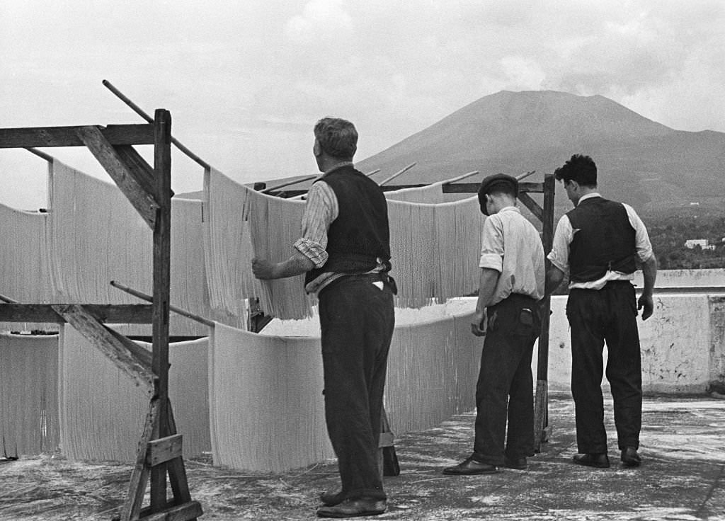 #64 Spaghetti production Hanging up spaghetti to dry them; in the background Mount Vesuvius, 1932