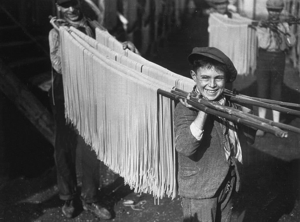 #70 A young boy carrying strings of pasta in a macaroni factory in Naples, Italy. 1929