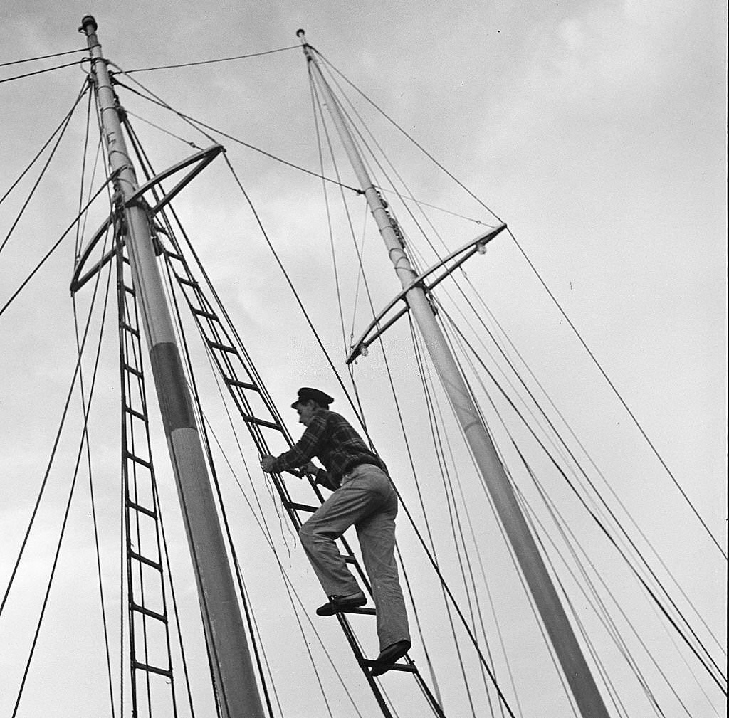 #102 A man climbs up the mast of a sailboat, Provincetown, Massachusetts, 1948.